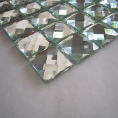 a close up of a glass mosaic tile on a table with white and gray squares