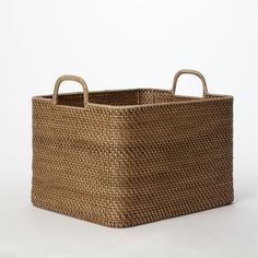 a woven basket with handles on a white background in the shape of a rectangle