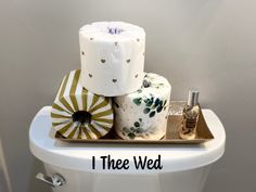 a toilet with two rolls of toilet paper on top of it and the words i thee wed above it