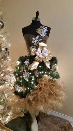 a mannequin is decorated with gold and white christmas wreaths in front of a tree