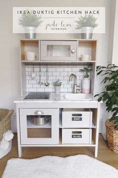 a white kitchen with an oven, sink and potted plants