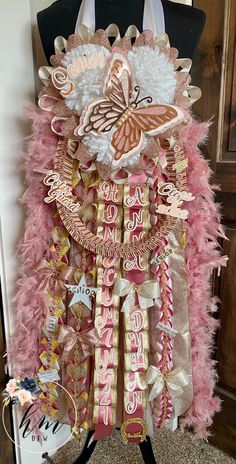 a mannequin is adorned with pink and gold ribbons, feathers, and butterflies