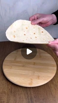 a person holding a tortilla on top of a cutting board