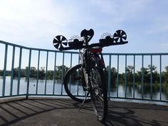 a bicycle parked on the side of a metal fence next to a body of water