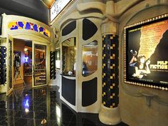 the inside of a movie theater with posters on the walls and black tile flooring