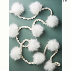 several white pom poms are tied up to a rope on a green surface