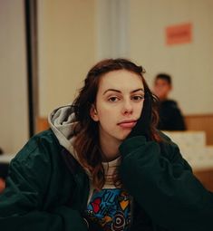 a woman sitting at a table with her hand on her head and looking off to the side