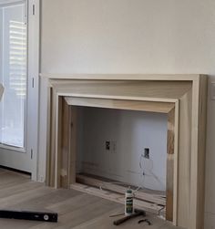 an unfinished fireplace being worked on in a living room with white walls and wood flooring