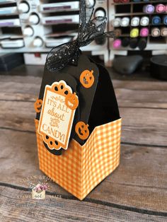 an orange and black halloween treat box on a wooden table with candy in the background