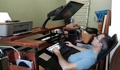 a man sitting at a desk working on a computer with a printer in the background