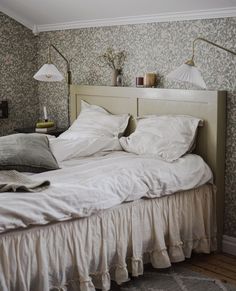 an unmade bed with two lamps on the headboard and one lamp above it