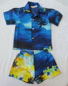 For your consideration is a vintage boy toddler button up shirt and matching shorts from Hawaii.  This is by Helena's.  It is a blue with the yellow sunset, palm trees and hibiscus.  Purchased in the 1980's.  Size is a 3. Fits like a 4T as it was purchased at the same time and the 4T's I also have listed.  The inside of the shorts are a white cotton.  No rips or stains. Thanks for looking.  Take a few minutes to check my other listing with many vintage, antiques, collectibles and more. Blue Short Sets For Beach, Blue Short Beach Sets, Summer Blue Short Sets, Blue Cotton Beach Season Sets, Yellow Short Sleeve Sets For Vacation, Yellow Short Sleeve Vacation Sets, Printed Short Sleeve Sets For Beach Season, Short Printed Beach Sets, Beach Short Sleeve Printed Sets