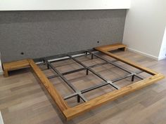 a wooden bed frame sitting on top of a hard wood floor next to a wall