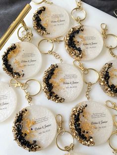 the keychains are decorated with black and gold glitters, which is on top of a white table