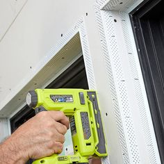 a man is using a cordless drill to fix a window sealer on the side of a building