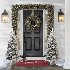 two christmas wreaths on the front door of a house