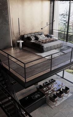 a bed sitting on top of a wooden floor next to a metal stair case in a living room