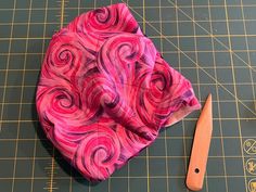 a pair of scissors sitting on top of a cutting board next to a piece of cloth