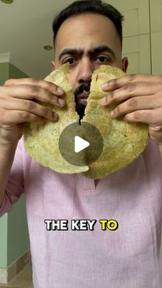 a man holding up a piece of bread in front of his face