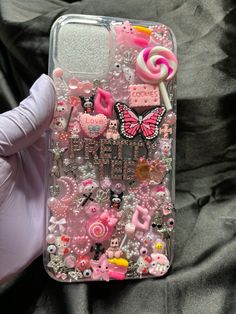 someone is holding up their phone case with many different things on it, including candy and candies