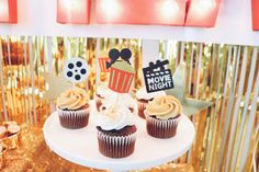 some cupcakes are sitting on a white cake platter with gold foil decorations