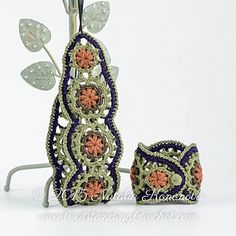 a crocheted vase and pot holder with flowers on it, sitting next to each other