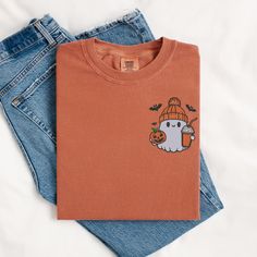 Get into the Halloween spirit while celebrating your love for autumn and caffeine with this adorable embroidered t-shirt! 👻 ## 📝 HOW TO ORDER: 1) Choose your size from the first dropdown    (TIP: For a looser fit, consider sizing up) 2) Select your shirt color from the second dropdown ## 📏 SIZING AND MATERIAL - Comfort Colors C1717 - Unisex fit (see size chart in images) - 6.1 oz., 100% ringspun cotton - Preshrunk, soft-washed, garment-dyed fabric ## 🎨 DESIGN DETAILS - Embroidered design pla Casual Embroidered Fall T-shirt, Casual Embroidered T-shirt For Fall, Fall Embroidered Graphics Short Sleeve T-shirt, Fall Cotton T-shirt With Embroidered Graphics, Cute Custom Embroidered Tops For Fall, Fall Embroidered Graphics Cotton T-shirt, Fall Embroidered Short Sleeve T-shirt, Cute Tops With Custom Embroidery For Fall, Embroidered Short Sleeve T-shirt For Fall