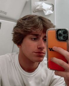 a young man taking a selfie with his cell phone in front of the camera