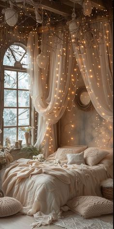 a bedroom with lights strung from the ceiling and curtains on the windowsill, along with a bed covered in white linens