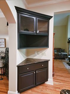 an entertainment center in the middle of a living room with wood floors and white walls