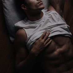 a man laying on top of a bed with his arm around the back of him