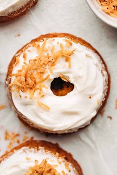 three donuts with white frosting and orange sprinkles sitting on a table