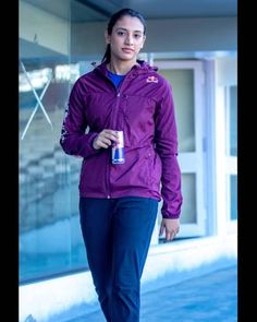 a woman is walking down the street with a water bottle in her hand