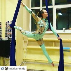 a woman is doing aerial acrobatic tricks in a room with yellow walls