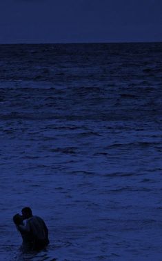 a man standing in the ocean at night