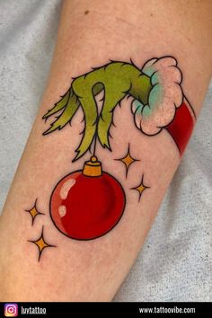 a person with a tattoo on their leg and arm holding a christmas ornament