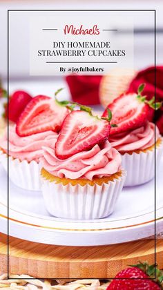 strawberry cupcakes with pink frosting and fresh strawberries on the top, sitting on a white plate