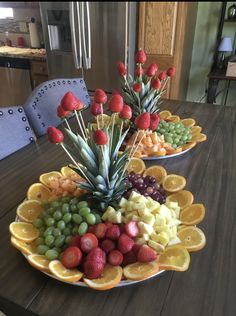 two plates filled with fruit and pineapples on top of a dining room table