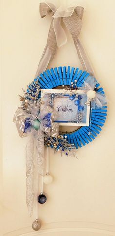 a blue wreath hanging on the side of a wall with a photo frame attached to it