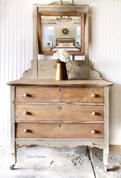 an old dresser with a mirror on top of it and a vase in the middle