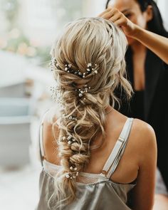 a woman is getting her hair done by another woman who is wearing a silver dress