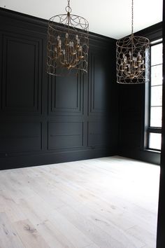 an empty room with black walls and chandeliers