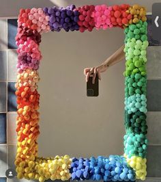 a person taking a photo in a mirror made out of colored pom poms