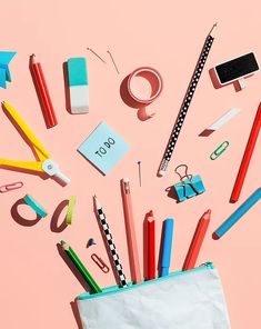 an assortment of office supplies on a pink background