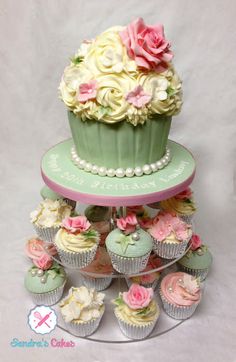 a three tiered cake with cupcakes and flowers on the top, in pastel colors