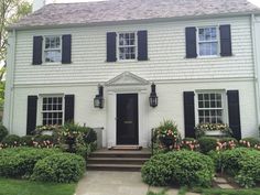 a white house with black shutters and flowers