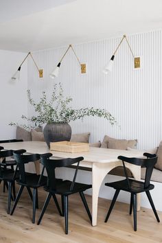 a dining room table with black chairs and a plant in the center on top of it