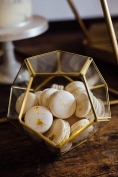 a glass bowl filled with macaroons on top of a wooden table