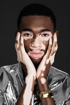 a man with mud all over his face and hands on his face, posing for a magazine cover