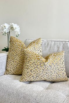 two pillows on a couch with flowers in the background